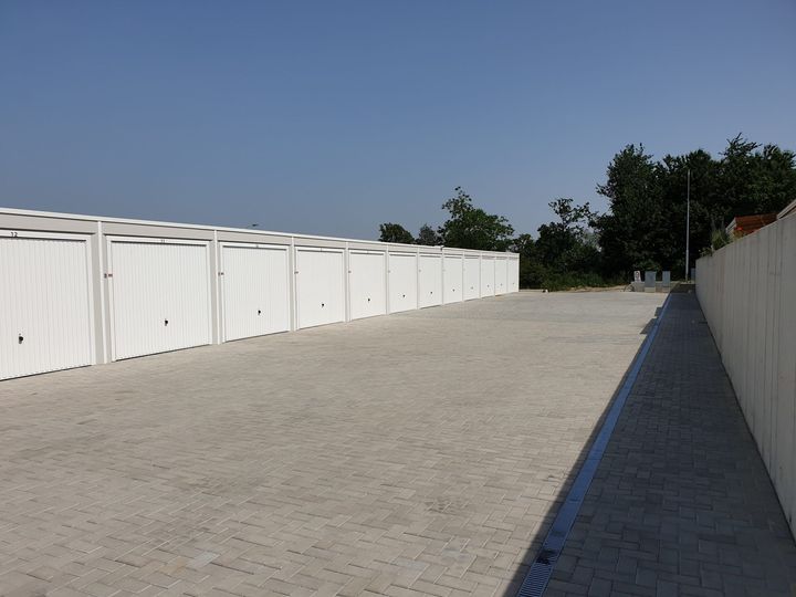 Garagenzeile entlang der gepflasterten Zufahrt