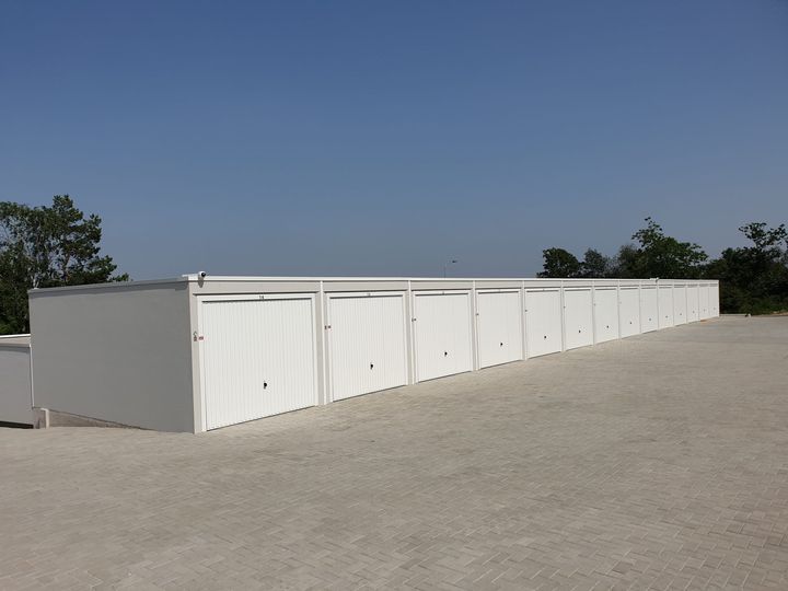 Garagenzeile des Garagenparks Göllersdorf mit weißen Schwingtoren vor blauem Himmel
