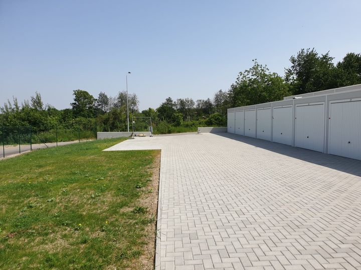 Gepflasterte Hoffläche mit Grünstreifen und Garagen am Rand